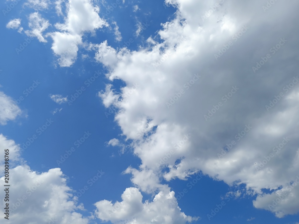 Obraz premium Large dense white and grey clouds in a blue sky. Dynamic summer weather skyscape background