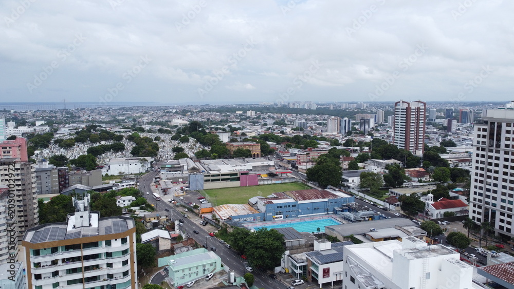 Fototapeta premium Drone Manaus-Amazonas-Brazil Aerial view of a sprawling city with a large cemetery and a swimming pool complex under a cloudy sky
