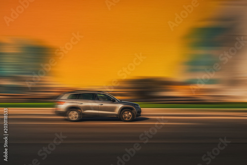 Fast moving car side view. Moving car with speed blur effect on blurred orange background