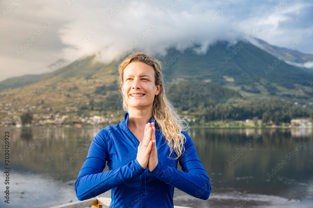 Fototapeta premium Woman smiling, finding balance and mindfulness during a yoga practice near a calm lake