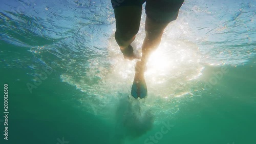 Underwater view of man snorkeling with flippers in clear blue ocean
