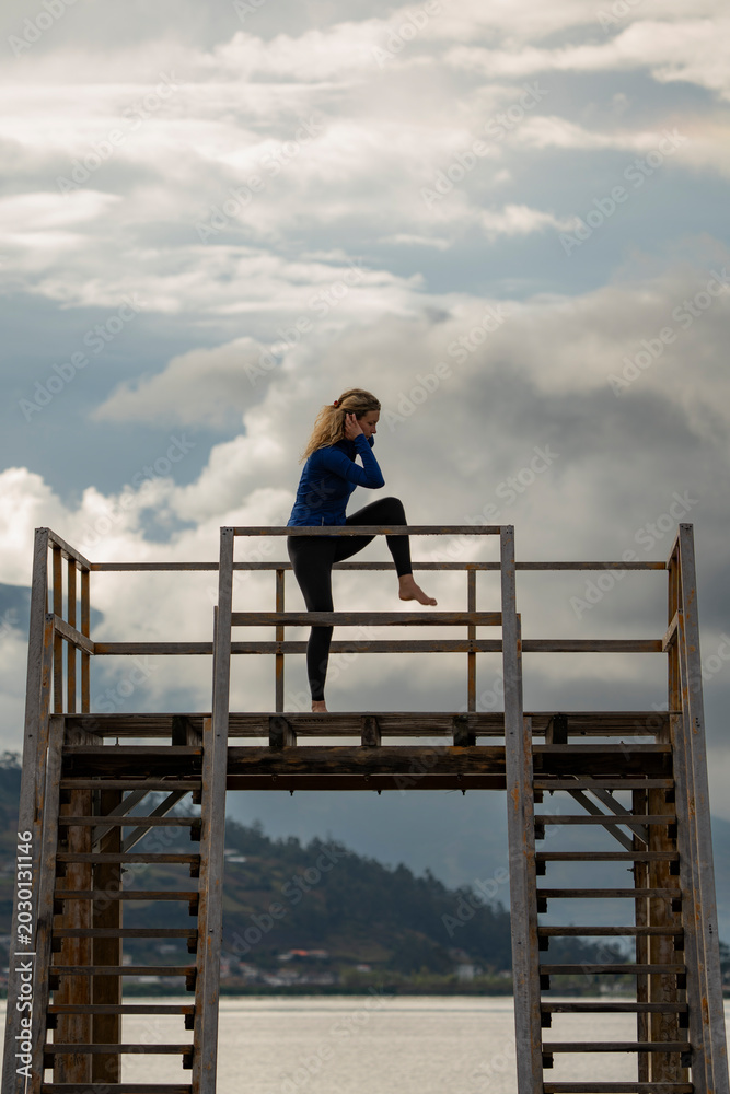 Fototapeta premium Woman performing a yoga pose on a wooden pier overlooking yahuarcocha lake