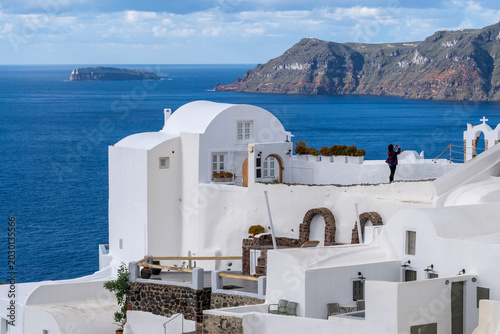 Foto A traveler capturing the scenic volcanic caldera bay view from a traditional whitewashed building terrace in Oia town, Santorini island, Greece