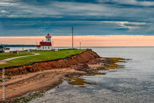 Photography Wood Islands Lighthouse on the south coast of Prince Edward Island, Canada, above red cliffs and shoreline at dusk