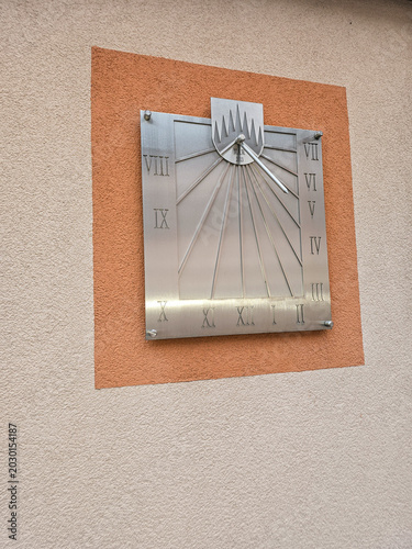 Modern metal sundial on a textured wall