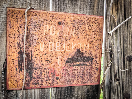 Rusty vintage warning sign in czech on a wooden fence