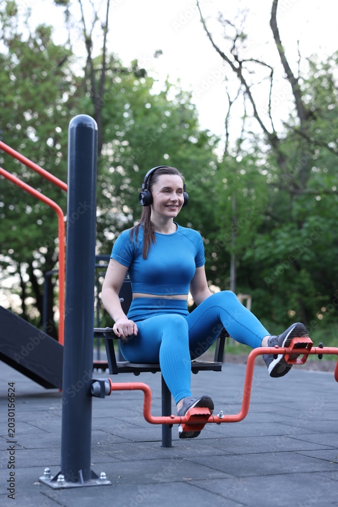 Obraz premium Athletic woman training on exercise bike at outdoor gym