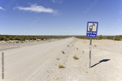 Signpost to a place with mobile phone reception next to endless gravel road, desert of the peninsula Valdes, Patagonia, east coast, Atlantic Ocean, Argentina