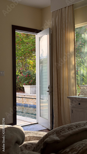 Canvas Print Open door revealing pool area from cozy bedroom interior