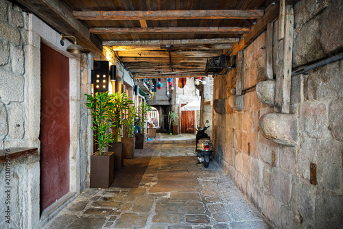 A narrow covered stone alleyway with shops and cafes in the historic Ribeira district of Porto, Portugal.
