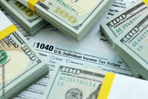 Konstfotografi 1040 Individual Income tax return form and hundred dollars money bills packs on