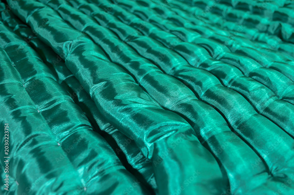 Fototapeta premium close-up of a green floor mattress with soft, textured, wavy fabric and a glossy sheen