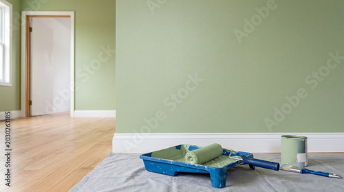 Freshly painted wall with plastic paint roller tray on floor clean interior home renovation concept