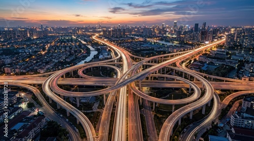 A stunning aerial photograph captures a sprawling cityscape at dusk. A complex network of elevated highways intertwines, creating a mesmerizing web of roads.