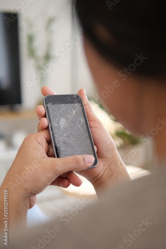 Person looks at a cracked phone screen in a living room