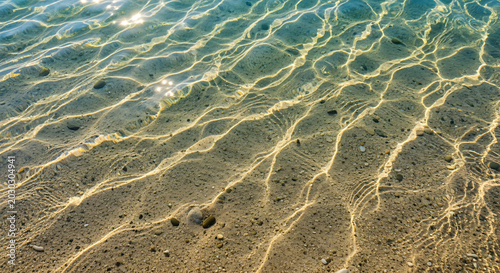 Sunlit Water Surface Over Sandy Seafloor Beach