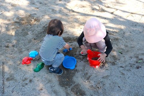 Two little children playing with toys in a sandbox at a park in Japan