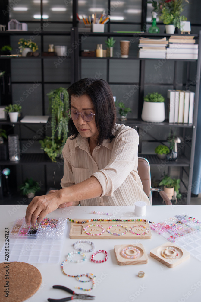 Fototapeta premium Mature asian woman making handmade jewellery accessories handcraft hobby