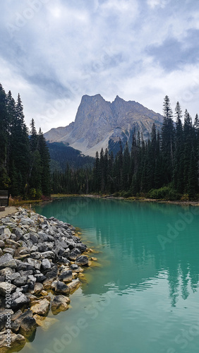 Scenic view of turquoise glacial lake with rocks in the foreground and majestic mountains