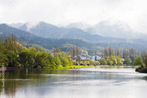 The mountains beside the river are shrouded in mist.
