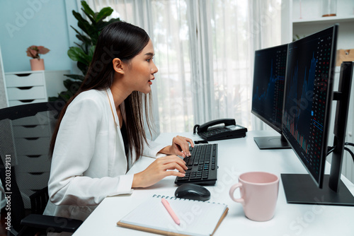 Schilderij op canvas Young beautiful Asian businesswoman looking on pc to analyze profitable of exchange stock market graph at modern office