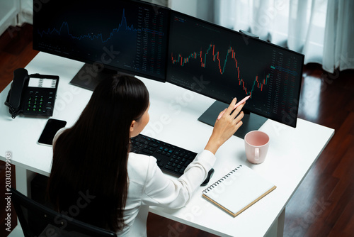 Schilderij op canvas Young beautiful Asian businesswoman looking on pc to analyze profitable of exchange stock market graph at modern office