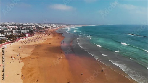 Rising drone shot tilts down over the beach in Agadir Morocco with waves