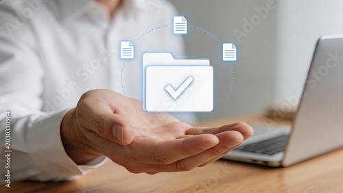 Digital folder icon with checkmark and document files floating above hand, representing cloud storage verification, data management approval and secure file organization systems.