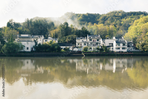 The mountains beside the river are shrouded in mist.
