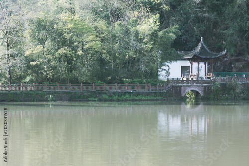 The pavilion is in the forest by the river.