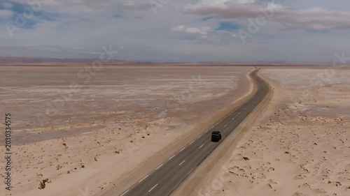Aerial drone view of an off-road track cutting across the immense dry surface of Chott el Djerid salt lake. Crystalline salt flats and vast desert horizon in southern Tunisia
