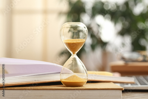 Hourglass with books and la...