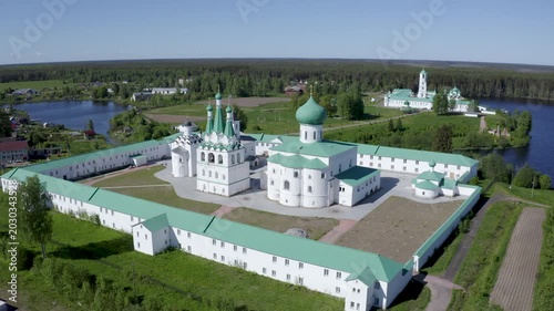 Orbital drone shot of Alexander-Svirsky Monastery and Roshchinskoe lake on sunny day. Leningrad Oblast, Russia.