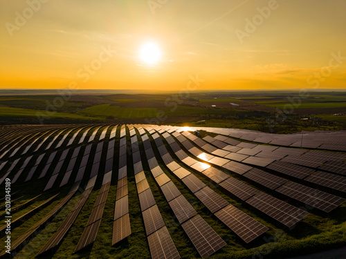 Obraz na płótnie Sunset over solar farm with rows of panels reflecting light in the fields of ren