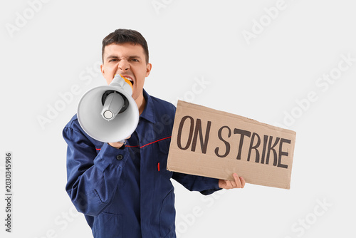 Protesting mechanic shouting into megaphone and holding placard with text ON ...