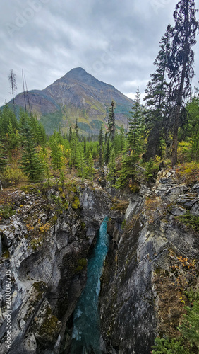 Deep rocky canyon with a turquoise river flowing below a high mountain peak
