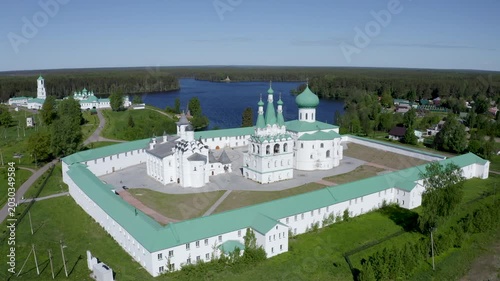 Forward reveal aerial shot of Alexander-Svirsky Monastery and Roshchinskoe lake on sunny summer day. Leningrad Oblast, Russia.