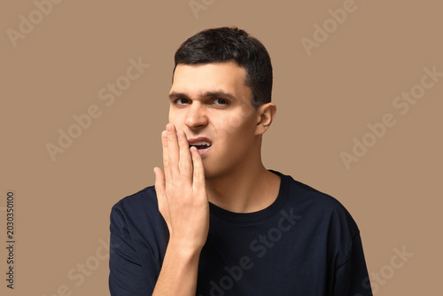 Foto Handsome young man feeling bad smell from mouth on beige background