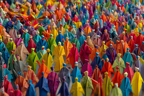 Large crowd of diverse people in colorful origami form inside a town