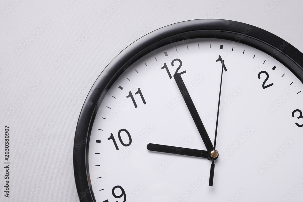 Fototapeta premium Round wall clock with black hands on a gray background. Time concept.