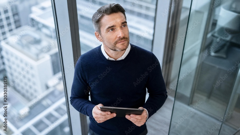 Fototapeta premium Pensive Professional Man Holding Digital Tablet in Modern Office with City View