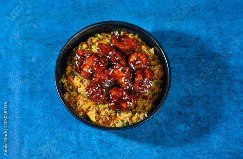 Quadro su tela A delicious bowl of spicy fried chicken sits on a blue table.