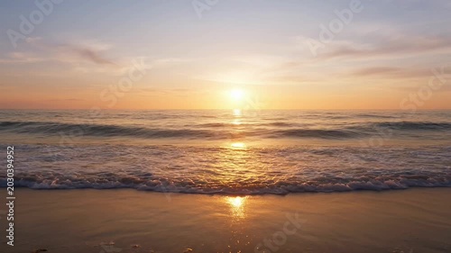 Sunset over calm ocean waves beach.