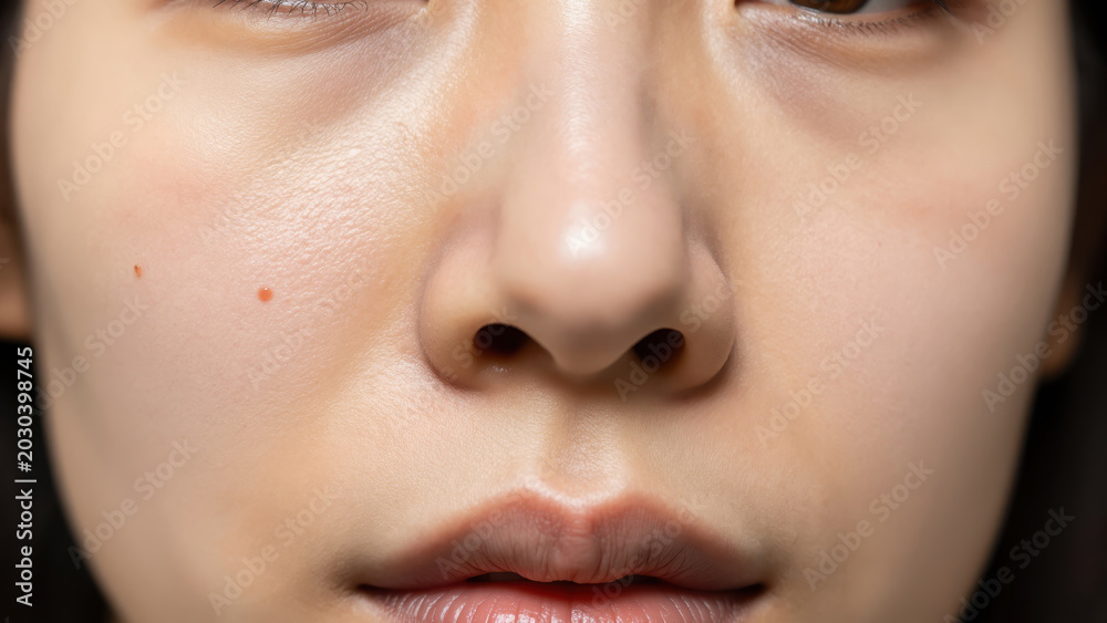 Naklejka premium Close-up of a young woman's flawless skin and serene expression, highlighting delicate features and a subtle, natural beauty.