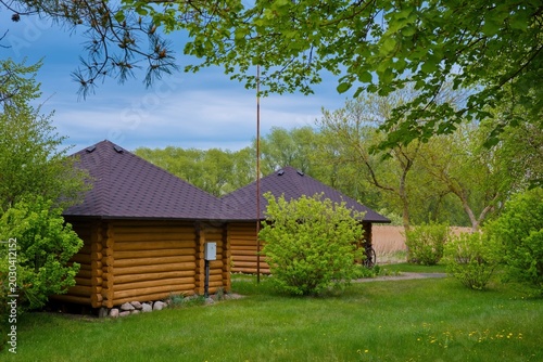 Konstfotografi Cozy wooden log cabins in a green rural park