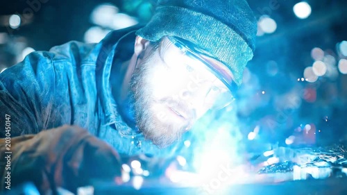 Master Welder at Work: A skilled welder, illuminated by the intense blue sparks of his craft, meticulously joins metal with precision and focus.