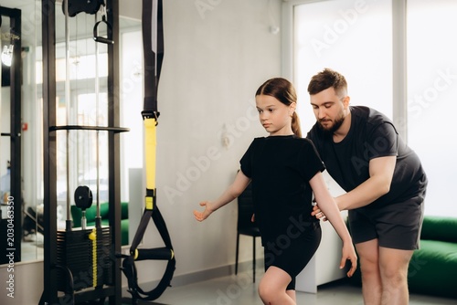 Child balancing during physiotherapy exercise with coach