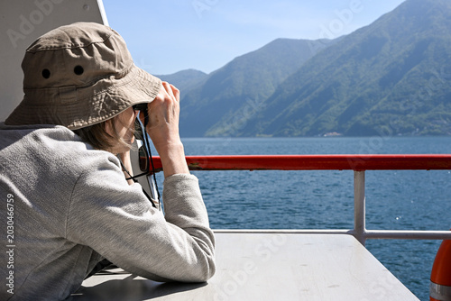 woman with binoculars on a boat in the Lugano lake in Ticino, Switzerland