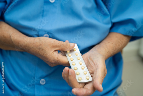 Photos Asian elderly woman holding pill drug in hand, strong healthy medical concept