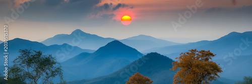 Sunset over mountain range with trees in foreground at dusk with colorful sky